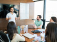 Young Hispanic presenter explaining business plan to coworkers in meeting room