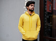 Urban young hipster indian man in a fashionable yellow sweatshirt. Cool south asian guy wear hoodie.