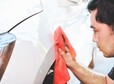 An Asian man owns a car wiping and cleaning the body paint of a car with a red cloth