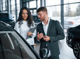 I'm very impressed about that new vehicle. Female customer and modern stylish bearded businessman in the automobile saloon.