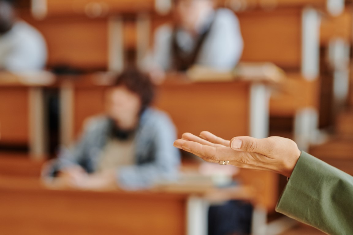 Hand of college or university teacher standing in front of audience and making speech about the main topic of lecture or seminar